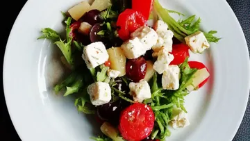 Colourful salad with feta cheese, tomatoes and green leafy vegetables.