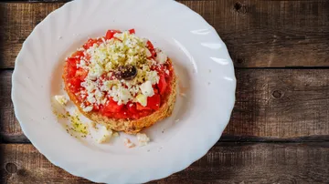 A sandwich with tomatoes, cheese and olives on a plate.