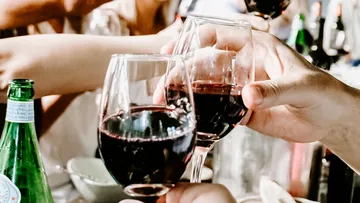 Gläser mit Rotwein stoßen in geselliger Runde an.