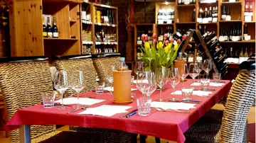 Ein gedeckter Tisch mit Gläsern und Blumen in einem Weinhaus.