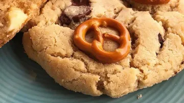 Keks mit Brezelstücken auf blauem Teller, appetitlich angerichtet.