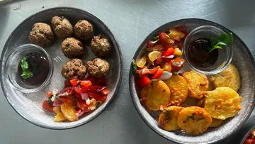 Meatballs and potato dishes with sauce and salad.