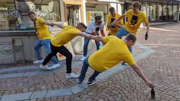 Sechs Männer in gelben T-Shirts dehnen sich auf dem Platz.