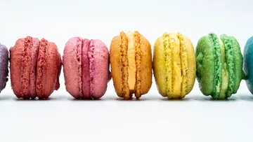 Bunte Makronen stehen nebeneinander auf weißem Hintergrund.