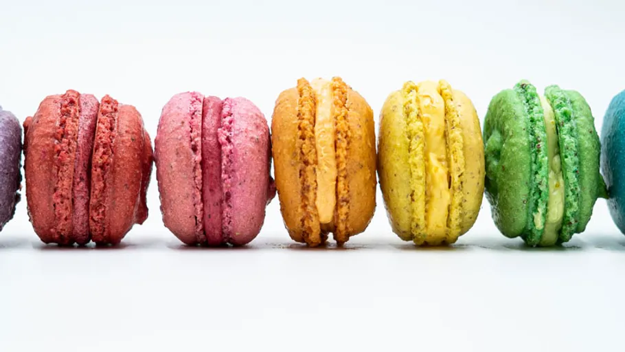 Colourful macaroons stand side by side on a white background.