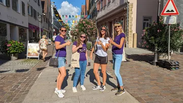 Vier Frauen stehen lächelnd auf einer Straße.
