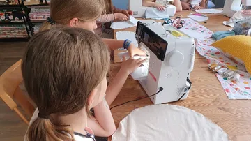 Sewing machine works while kids sew in creative space.