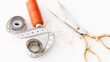 Sewing supplies lie on a table: scissors, thread, tape measure.