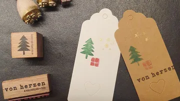 Geschenkanhänger zeigen Weihnachtsmotive auf einem dunklen Untergrund.