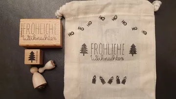 Holzstempel und Stoffbeutel mit Weihnachtsmotiven und Text.