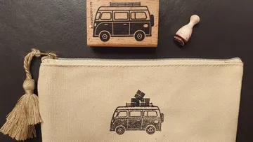 Tasche mit Busdruck und Holzstempel, auf dunklem Hintergrund.