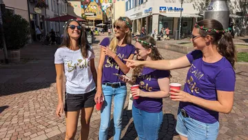 Four women are partying outdoors and laughing together.