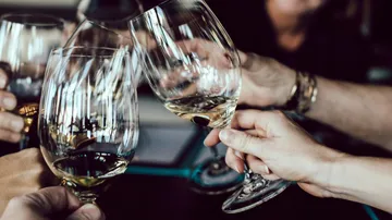 Glasses clink while people party in a busy room.