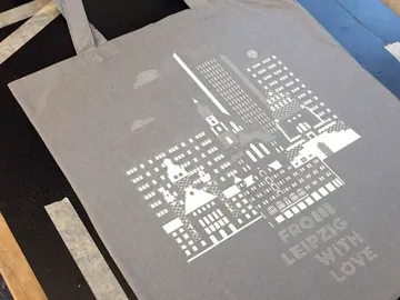 Graue Einkaufstasche mit Druck einer Stadtansicht und Text.