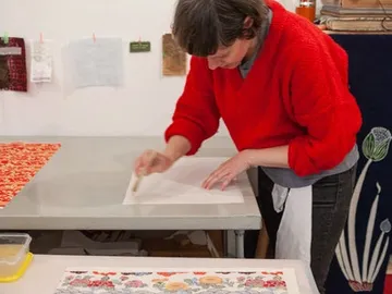 Woman wearing a red sweater is carefully working at the table.