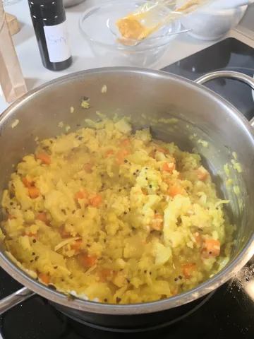 Topf mit gekochtem Gemüse und Reis auf dem Herd.