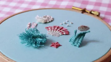 Stickerei zeigt maritime Motive auf blauem Stoff.