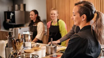 Four women are standing in a modern kitchen and studying.