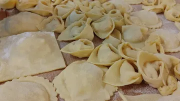 Homemade dumplings lie on a table top with flour.