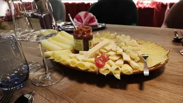 Cheese platter with various types of cheese and chutney, covered table.