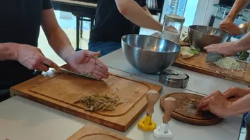 Köche schneiden Gemüse auf Holzplatten in einer hellen Küche.