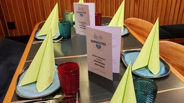 A set table with menu cards and colorful glasses.