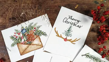 Christmas cards are laid out on a table with decorative elements.