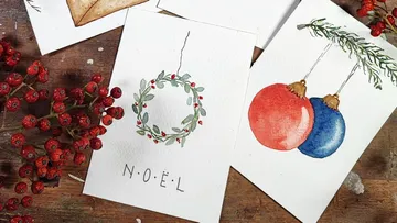 Cards with Christmas motifs lie on a wooden table.