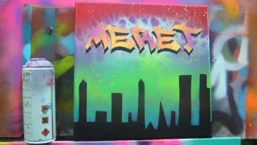 Spraydose neben bunter Graffiti-Leinwand mit Stadt-Silhouette.