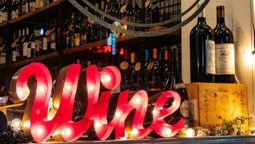 Glowing wine sign in front of wine racks in a shop