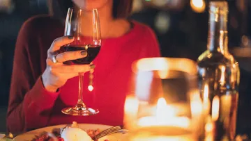 A person is holding a wine glass in a restaurant.