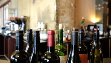 Wine bottles are on a table in a bar.
