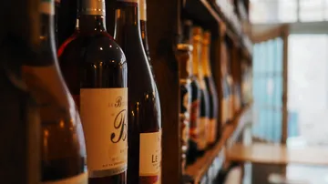 Wine bottles are placed on a wooden rack in a room.
