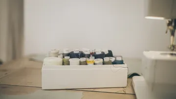 Ein Kasten mit Nähgarn steht auf einem Tisch.