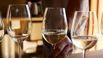Wine glasses are standing, someone is holding a glass of sparkling wine.