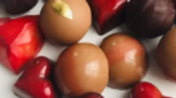 Heart-shaped and round chocolates lie on a plate.