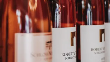 Bottles display pink wine on a shelf.