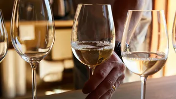 A glass of sparkling wine is held, surrounded by other glasses.