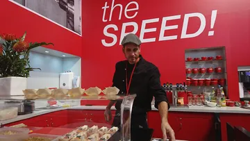 Koch prepares food in a red restaurant kitchen.