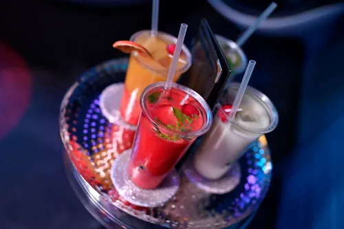 Vier bunte Cocktails stehen auf einem glitzernden Tablett.