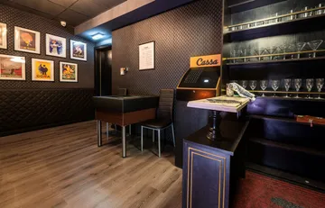 Elegante Bar mit Stühlen, Tischen und Bildern an der Wand.