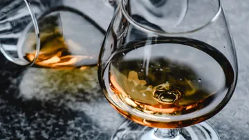 A glass of golden drink is on a table.