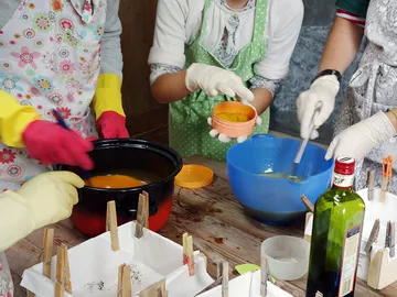 Several people mix colors in pots to create something.