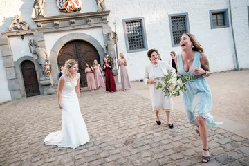 Bride happily walks up to guests in front of the castle.