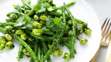 Green vegetables on a white plate, garnished with herbs.