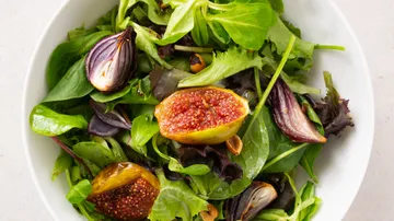 Green salad with figs and onions in bowl.