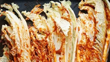 White cabbage strips in hot sauce on black background.