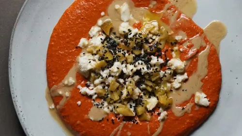 Rote Sauce mit Käse und gebratenen Früchten auf Teller.