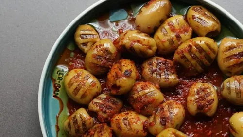 Grilled potatoes lie on a plate in a spicy sauce.