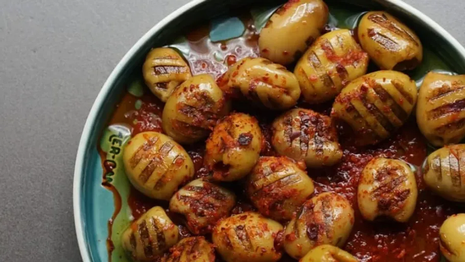 Grillkartoffeln liegen in einer würzigen Sauce auf einem Teller.